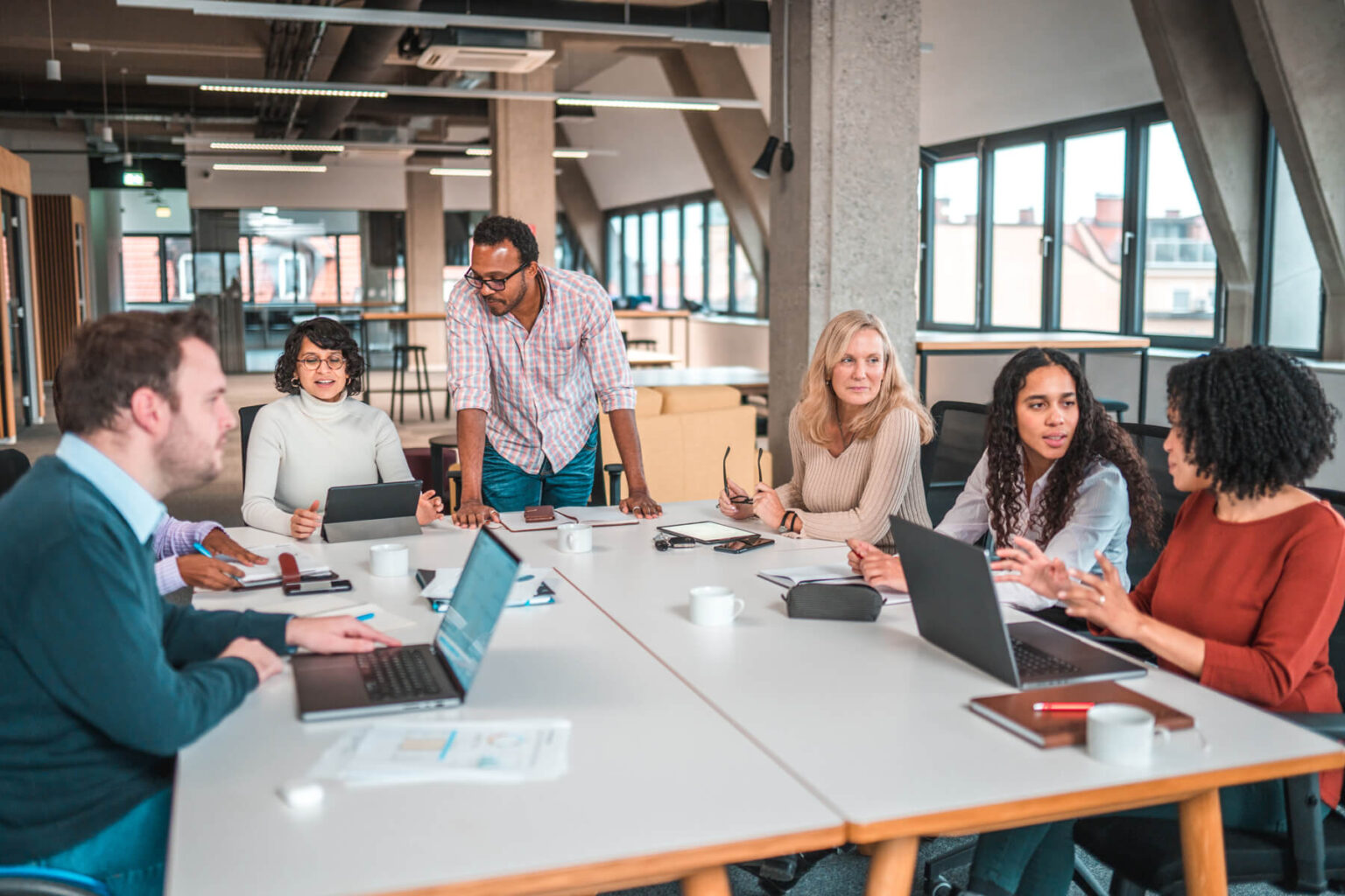 Group of coworkers gathered around a desk in a brightly lit office.